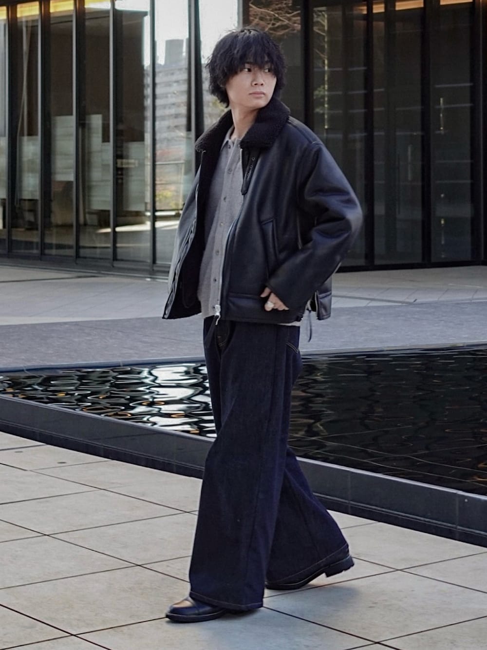 グレー系のニット/セーター、ブラック系のブルゾン、ブルー系のデニムパンツを着用したメンズの冬コーディネートの1枚目の写真