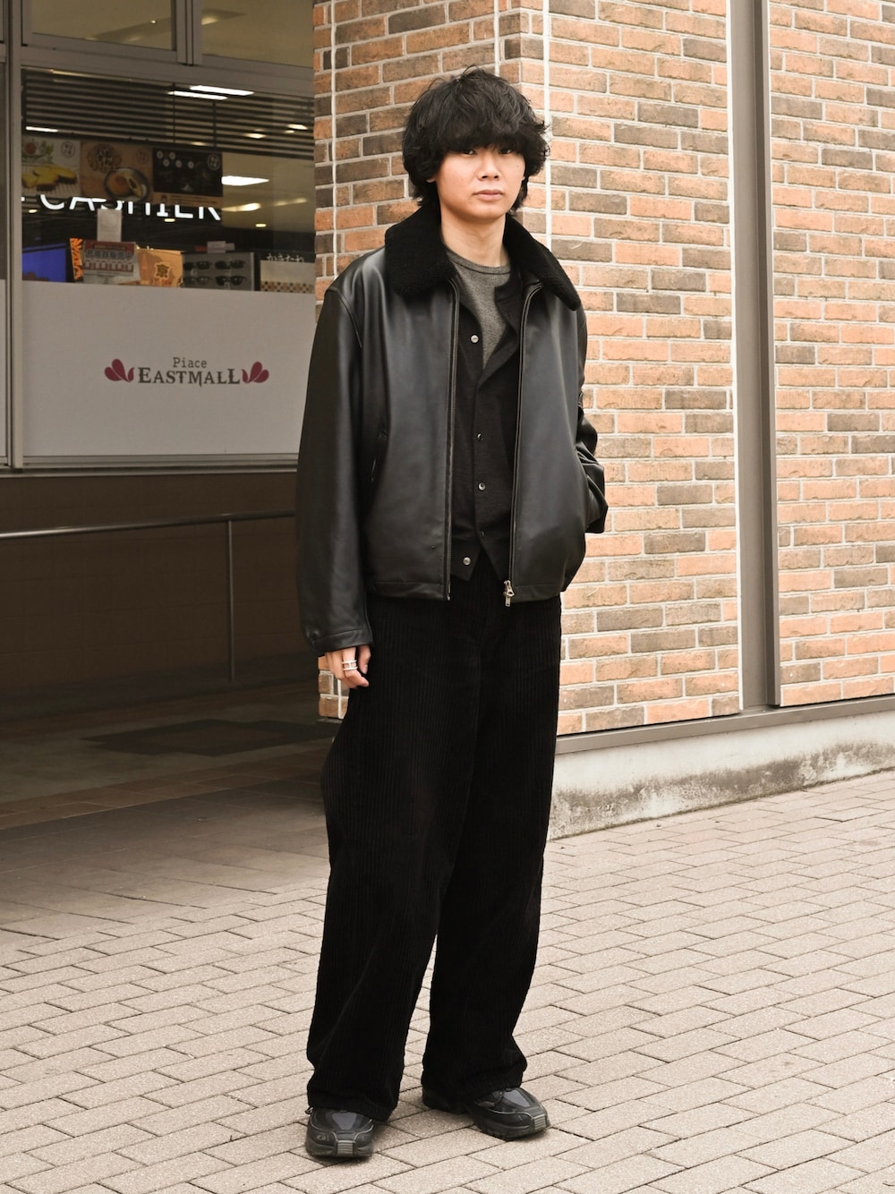 ブラック系のスニーカー、イエロー系のTシャツ/カットソー、ブラック系のブルゾンを着用したメンズの春コーディネートの1枚目の写真