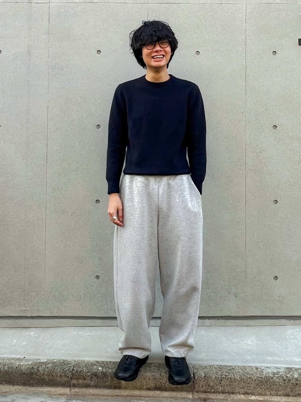 グレー系のスウェットパンツ、ブルー系のニット/セーター、ブラック系のスニーカーを着用したメンズの冬コーディネートの1枚目の写真