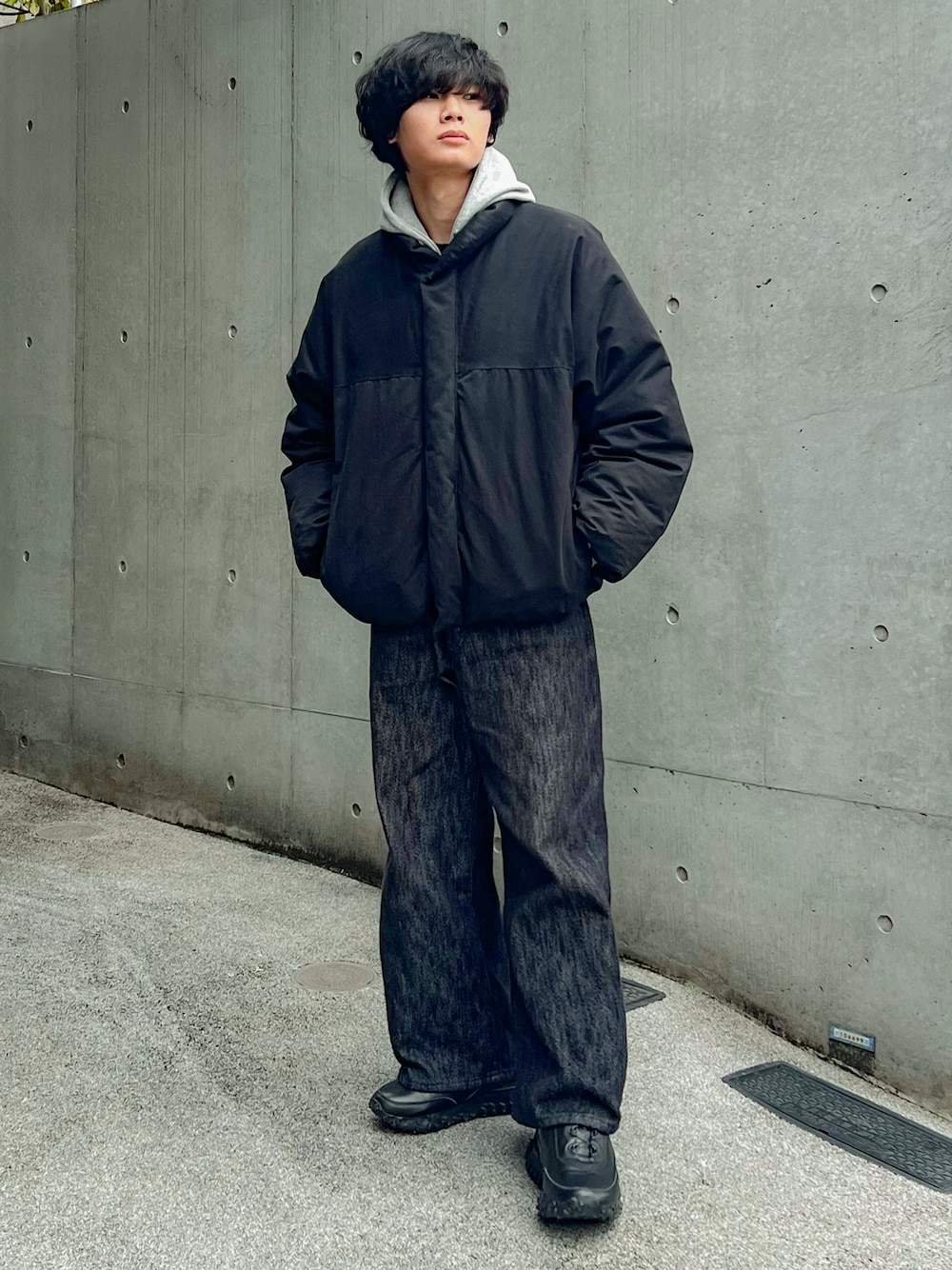 ブラック系のデニムパンツ、ブラック系のダウンジャケット/コート、グレー系のパーカーを着用したメンズの冬コーディネートの1枚目の写真