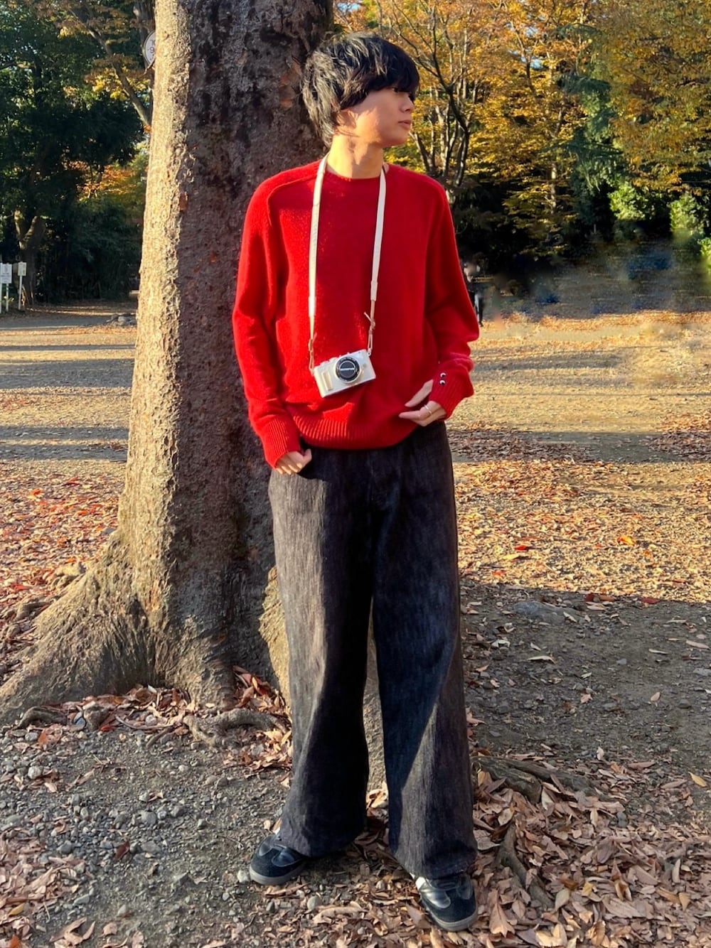 レッド系のニット/セーター、ブラック系のデニムパンツ、ブラック系のスニーカーを着用したメンズの冬コーディネートの1枚目の写真