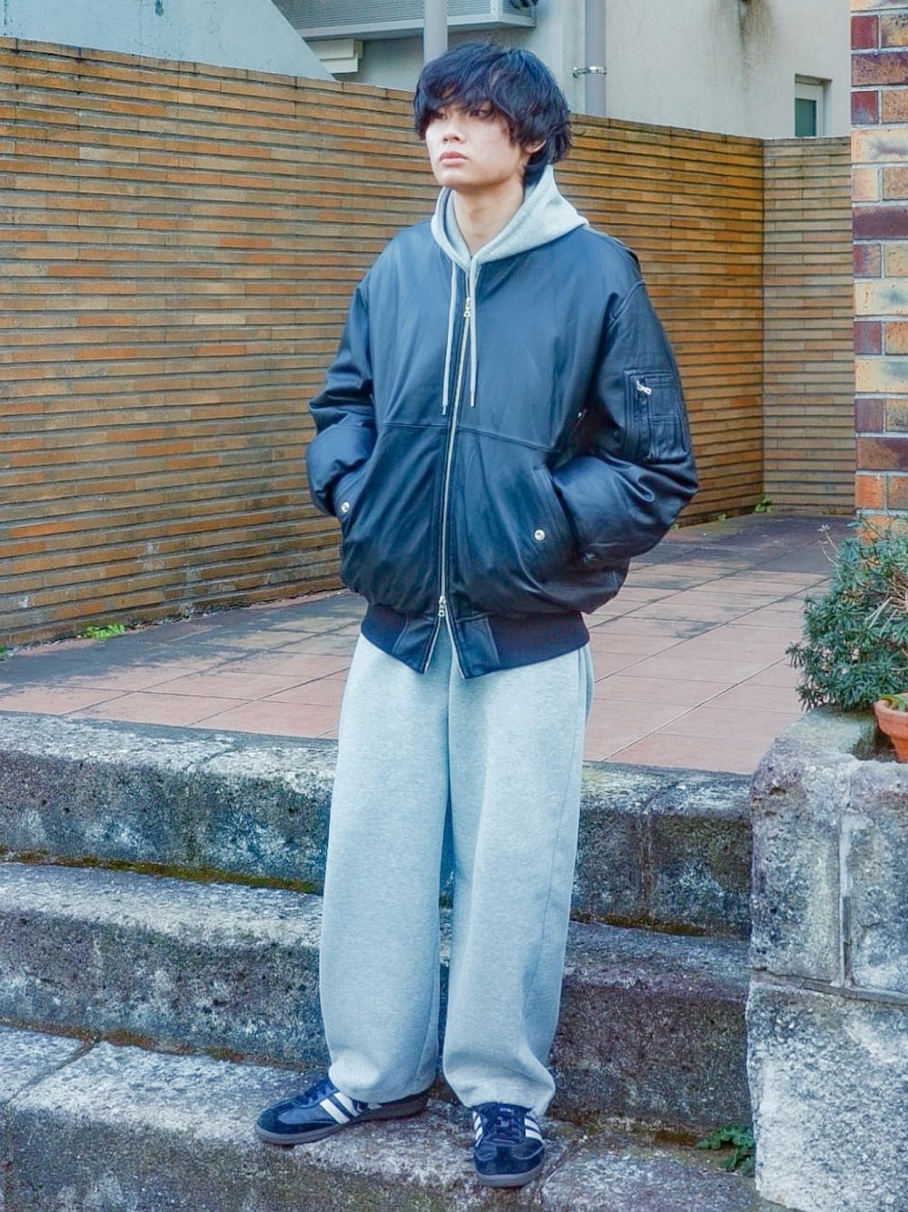 ブラック系のブルゾン、グレー系のパーカー、グレー系のスウェットパンツを着用したメンズの冬コーディネートの1枚目の写真