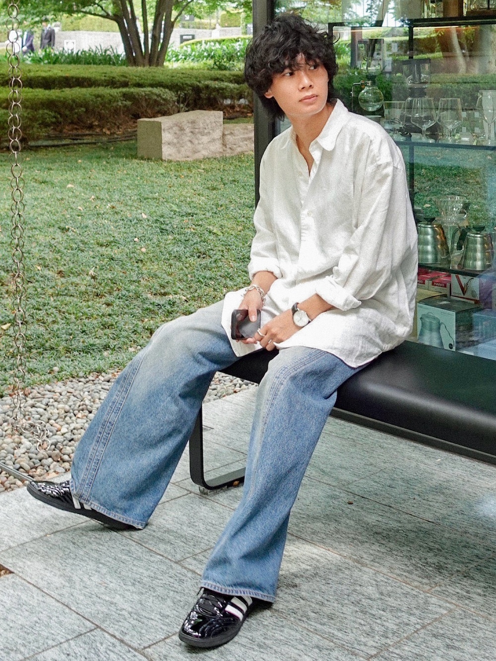 ブラック系のタンクトップ、ブラック系のスニーカー、ブルー系のデニムパンツを着用したメンズの夏コーディネートの1枚目の写真