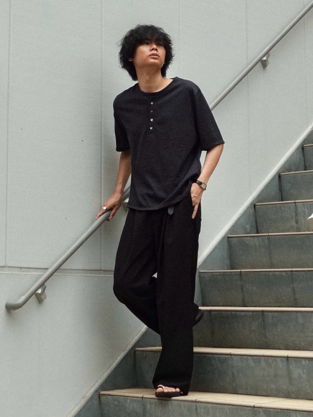 ブラック系のスラックス、ブラック系のサンダル、ブラック系のTシャツ/カットソーを着用したメンズの夏コーディネートの1枚目の写真