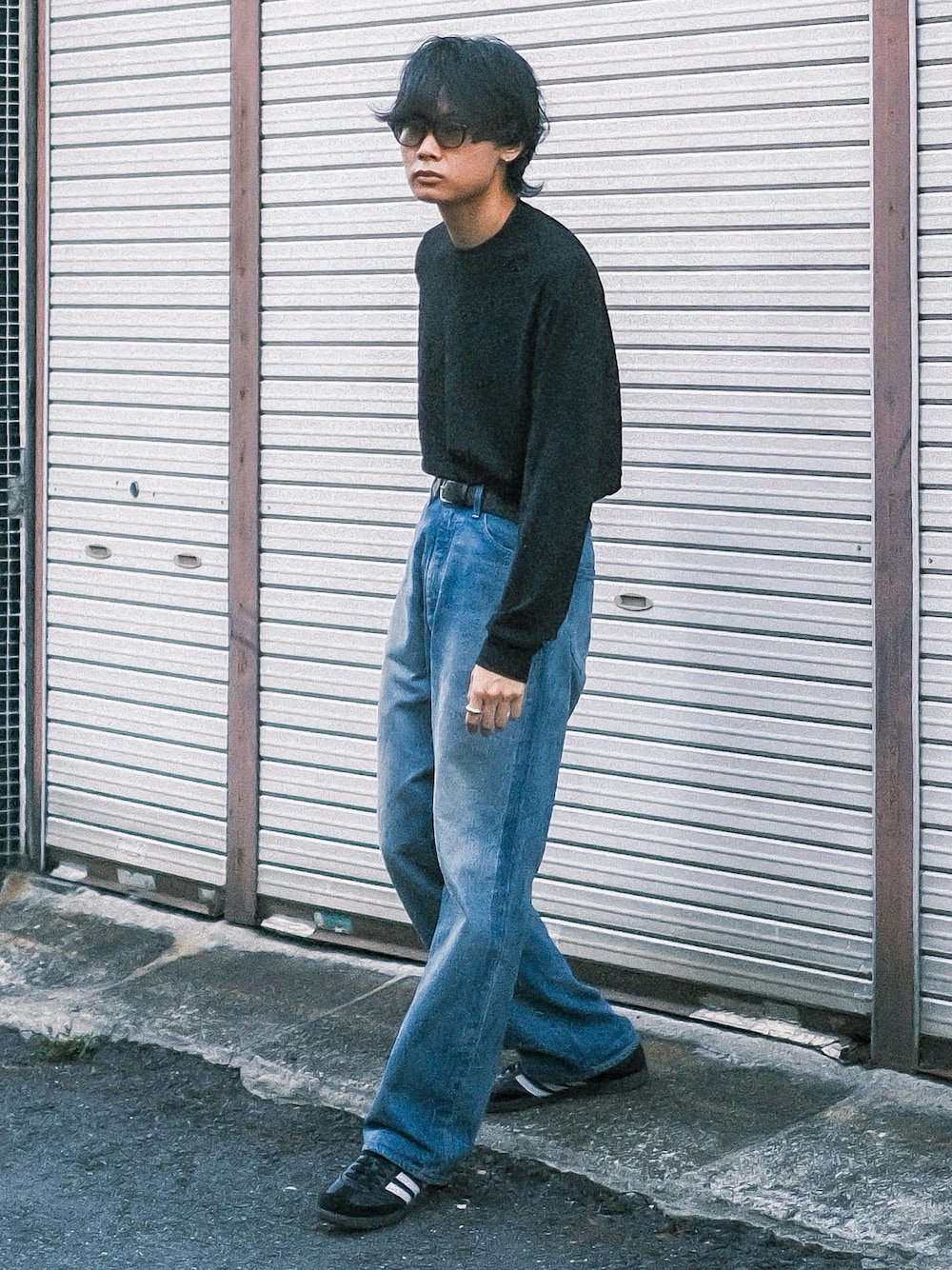 ブルー系のデニムパンツ、ブラック系のTシャツ/カットソー、ブラック系のスニーカーを着用したメンズの秋コーディネートの1枚目の写真