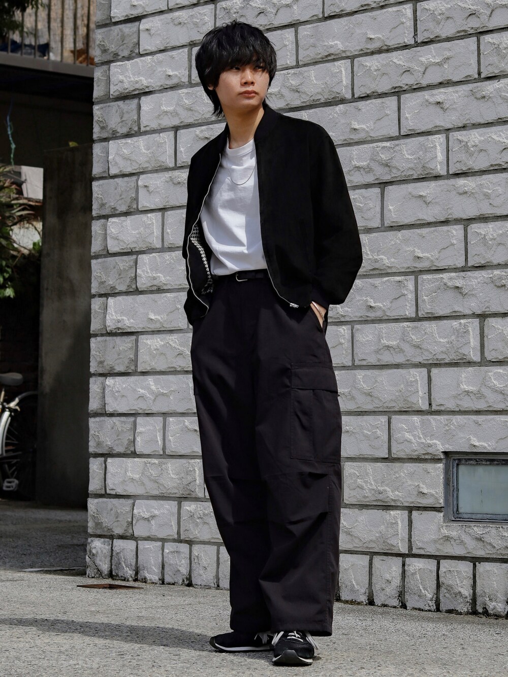 ブラック系のブルゾン、ホワイト系のTシャツ/カットソー、ブラック系のカーゴパンツを着用したメンズの春コーディネートの1枚目の写真
