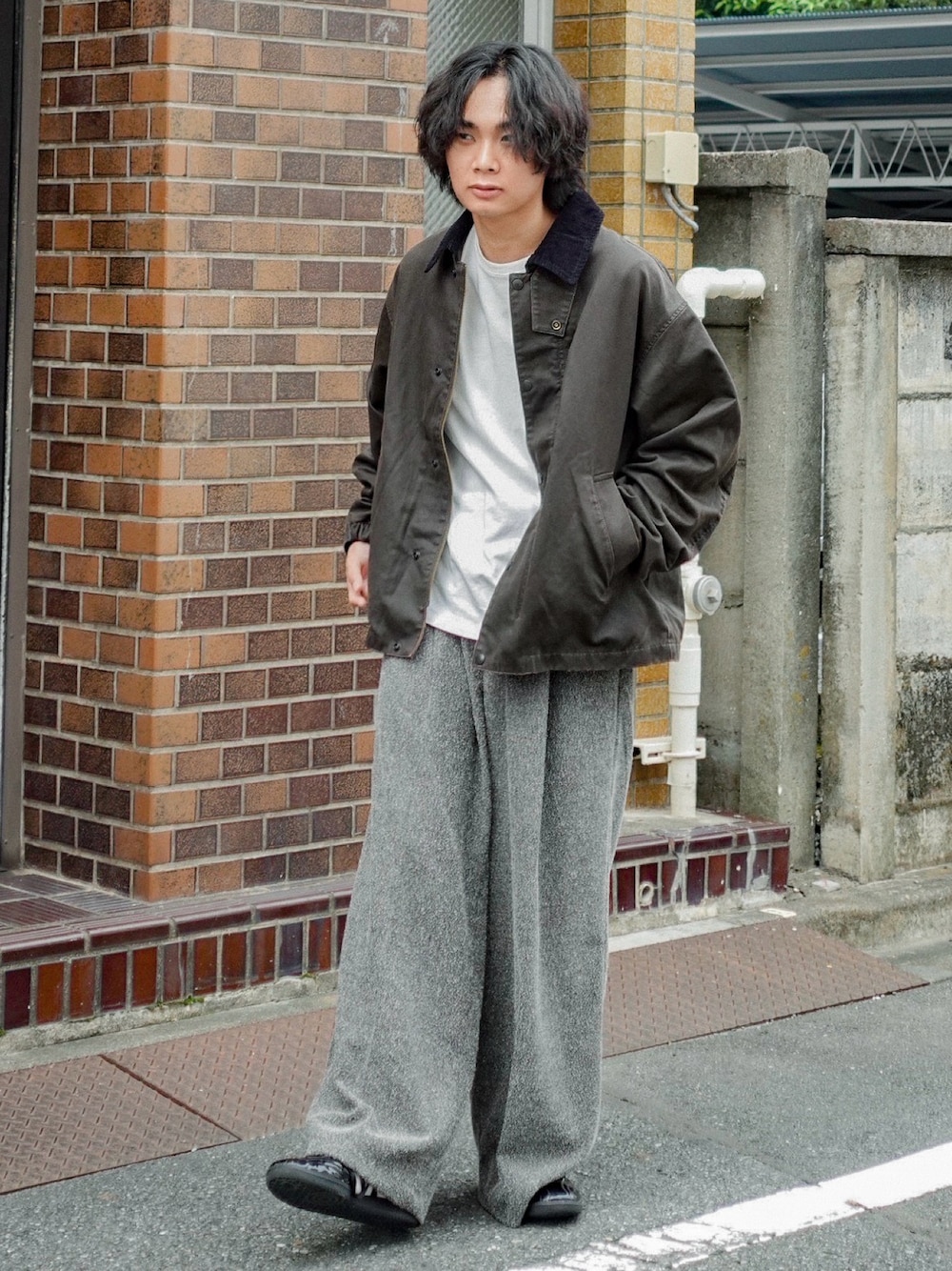 ホワイト系のTシャツ/カットソー、ブラウン系のブルゾン、グレー系のスラックスを着用したメンズの秋コーディネートの1枚目の写真