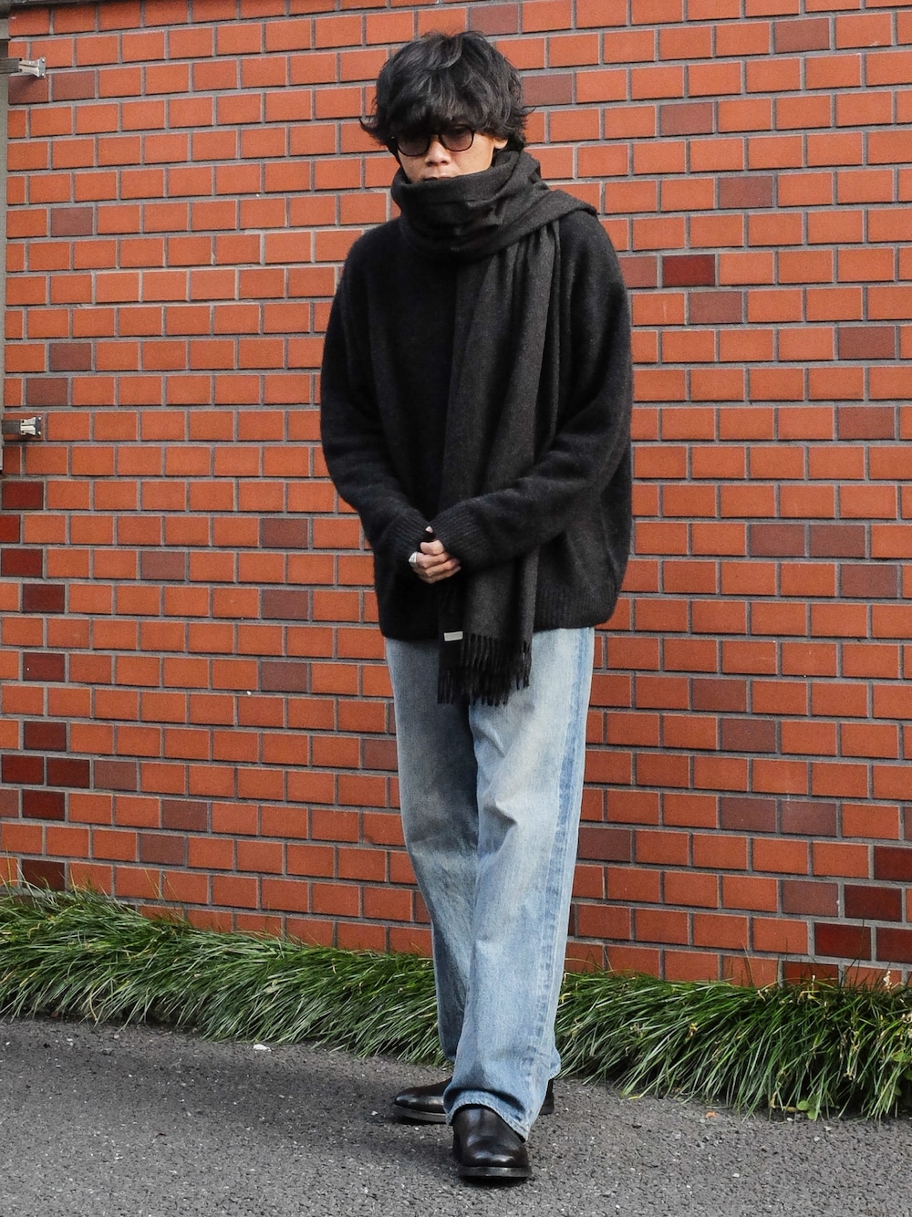 ブラック系のニット/セーター、ブルー系のデニムパンツ、ブラック系のブーツを着用したメンズの冬コーディネートの1枚目の写真