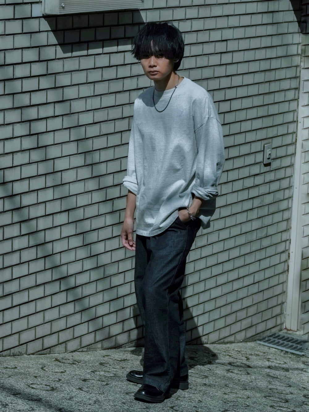 グレー系のTシャツ/カットソー、ブラック系のドレスシューズ、ブルー系のデニムパンツを着用したメンズの夏コーディネートの1枚目の写真