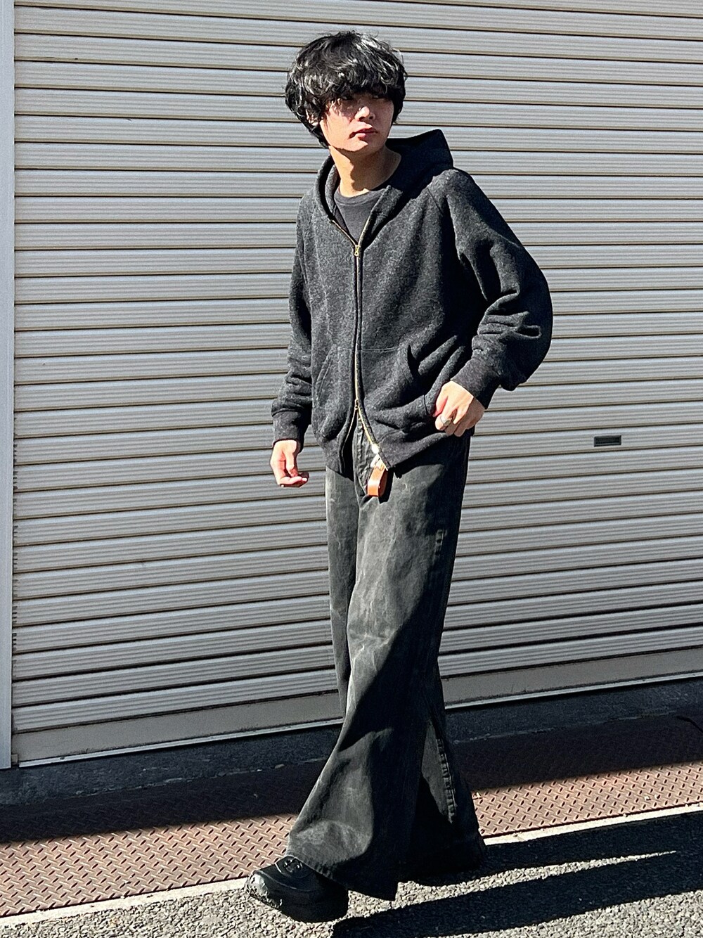 ブラック系のパーカー、ブラック系のデニムパンツ、ブラック系のスニーカーを着用したメンズの春コーディネートの1枚目の写真