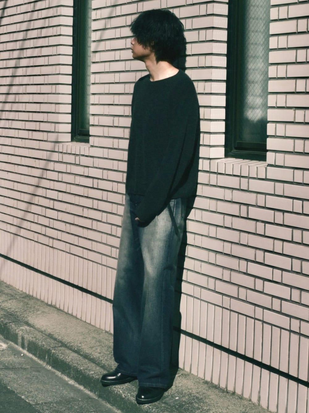 ブラック系のドレスシューズ、ブルー系のデニムパンツ、ブラック系のニット/セーターを着用したメンズの冬コーディネートの1枚目の写真