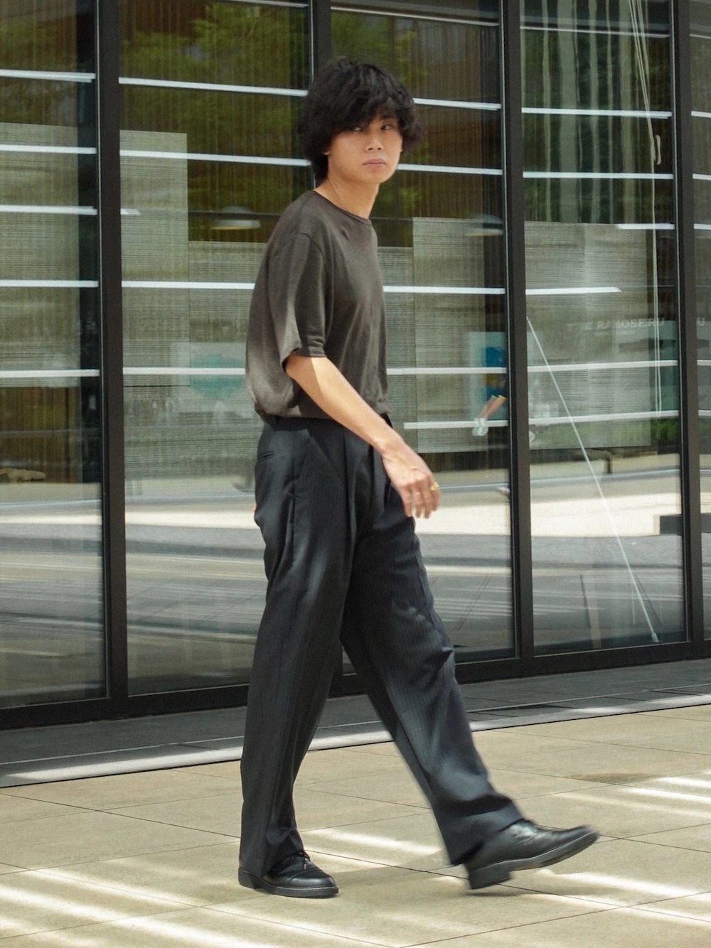 ブラック系のドレスシューズ、ブラウン系のTシャツ/カットソー、グレー系のスラックスを着用したメンズの夏コーディネートの1枚目の写真
