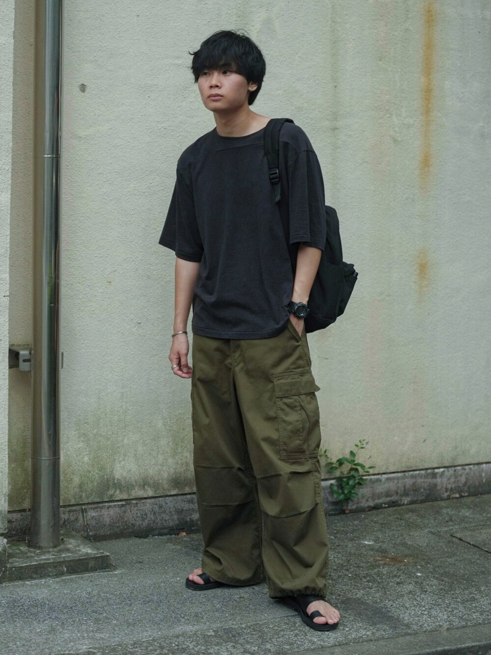 ブラック系のTシャツ/カットソー、ブラック系のバックパック/リュック、グリーン系のカーゴパンツを着用したメンズの夏コーディネートの1枚目の写真