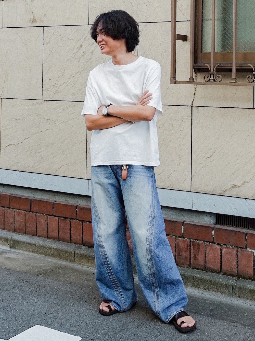 ホワイト系のTシャツ/カットソー、ブルー系のデニムパンツ、ブラック系のサンダルを着用したメンズの秋コーディネートの1枚目の写真