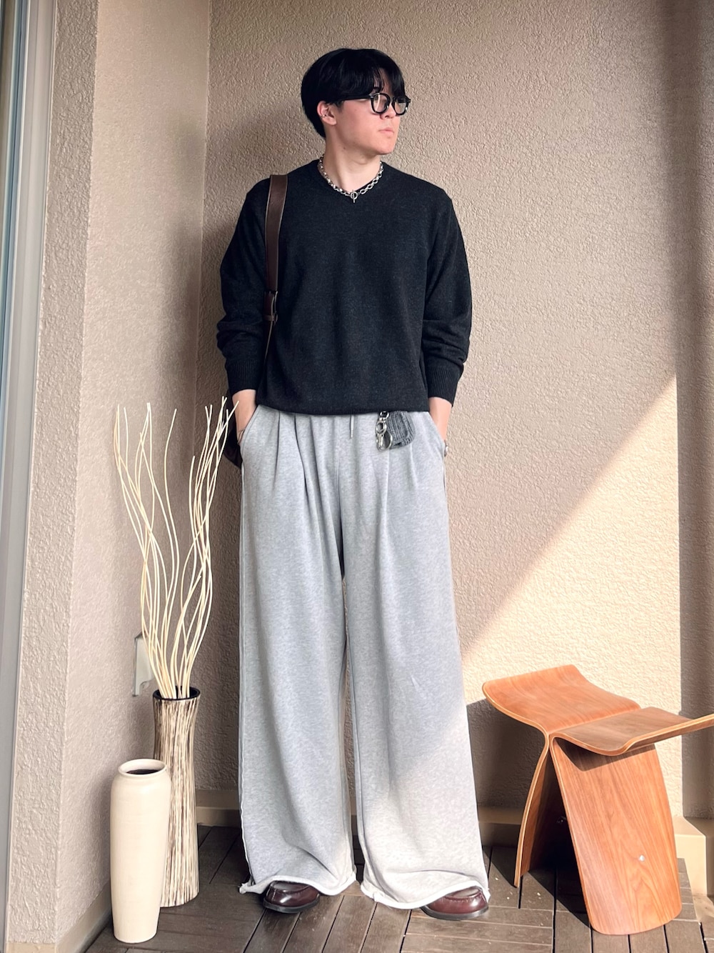 ブラウン系のショルダーバッグ、グレー系のニット/セーター、グレー系のスウェットパンツを着用したメンズの秋コーディネートの1枚目の写真