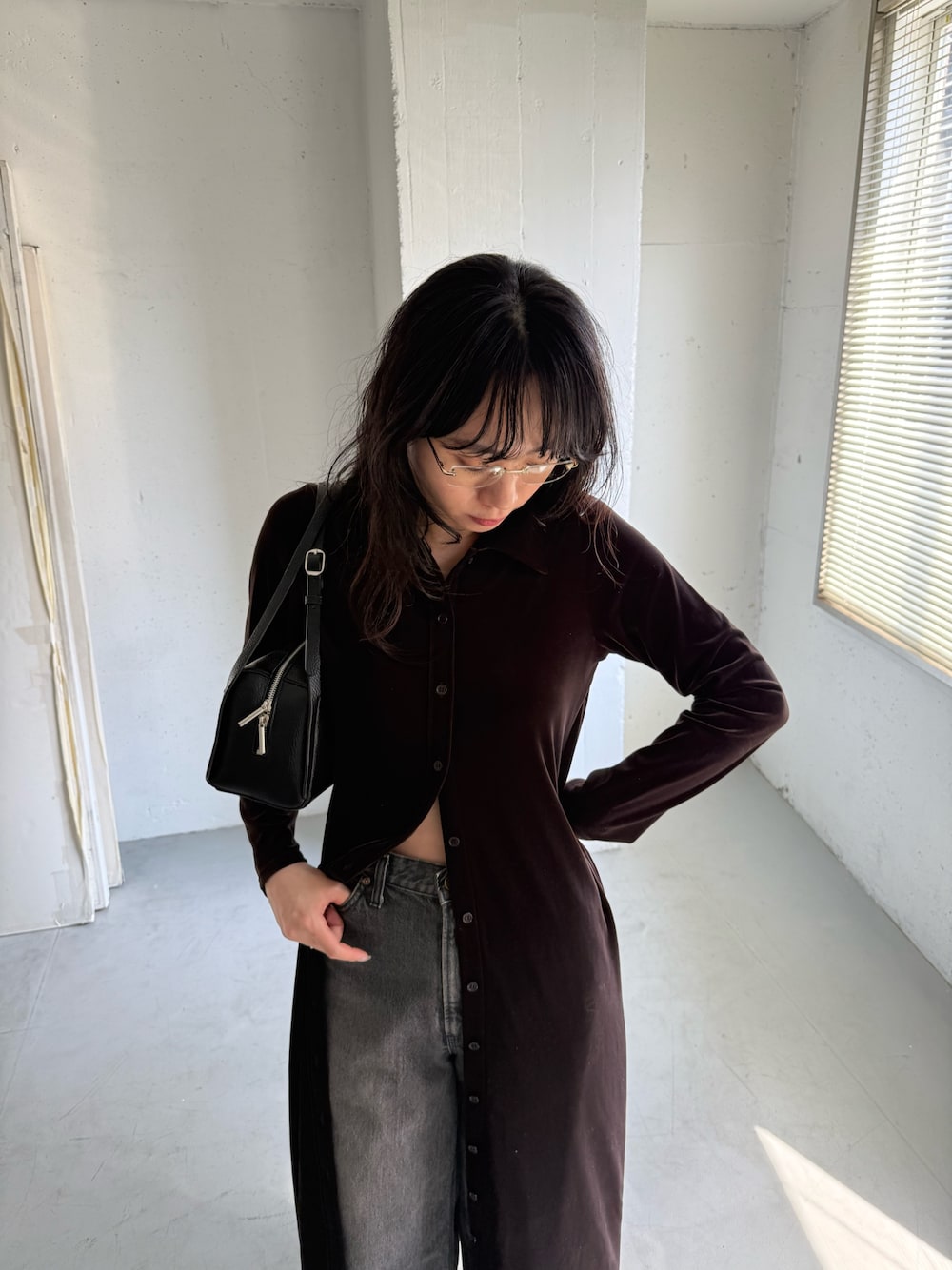 ブラック系のデニムパンツ、ブラウン系のワンピース、ブラック系のボストンバッグを着用したレディースの秋コーディネートの1枚目の写真