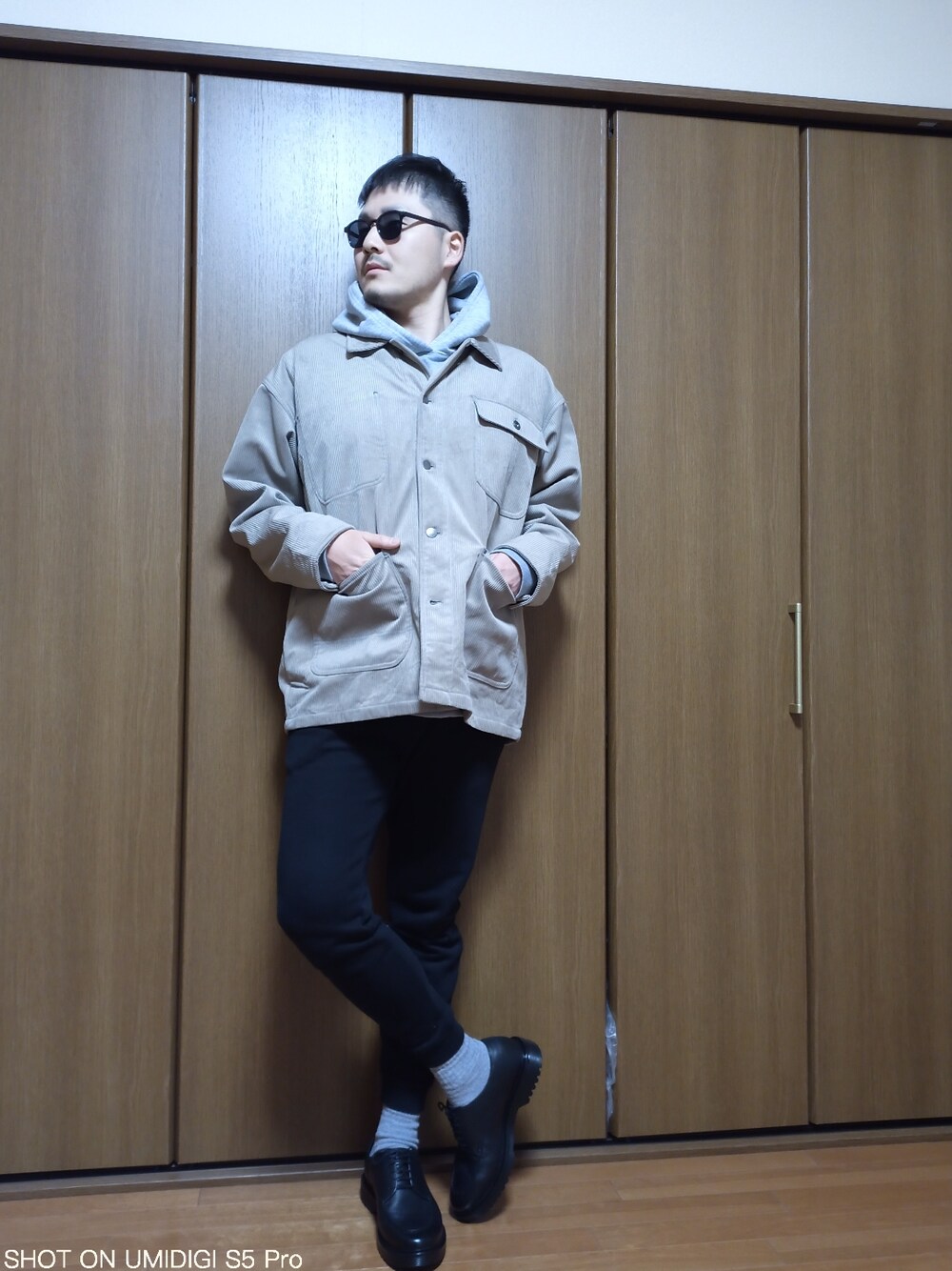 ブラック系のパンツ、ブラック系のシューズ、ベージュ系のカバーオールを着用したメンズの春コーディネートの2枚目の写真