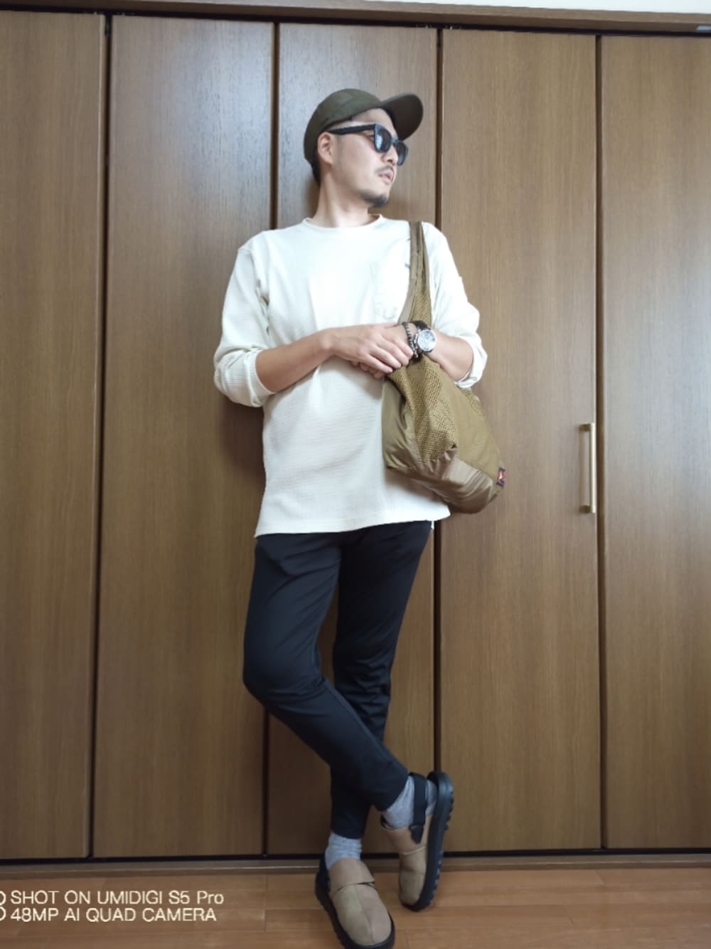 ブラック系のスウェットパンツ、ベージュ系のサンダル、ベージュ系のエコバッグ/サブバッグを着用したメンズの秋コーディネートの1枚目の写真