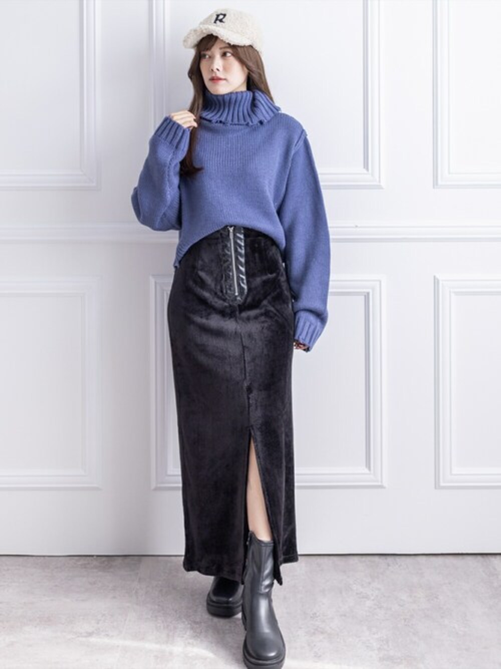 グレー系のニット/セーター、ブラック系のスカート、ブラック系のブーツを着用したレディースの冬コーディネートの1枚目の写真