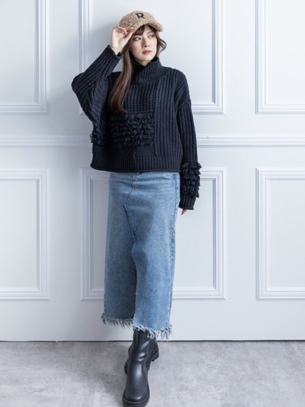 ブラック系のニット/セーター、ベージュ系のデニムスカート、ブラック系のブーツを着用したレディースの冬コーディネートの1枚目の写真