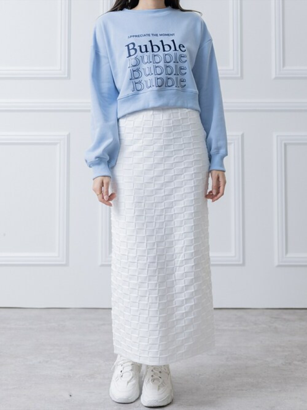 ブルー系のスウェット、ホワイト系のスカート、ホワイト系のスニーカーを着用したレディースの春コーディネートの1枚目の写真