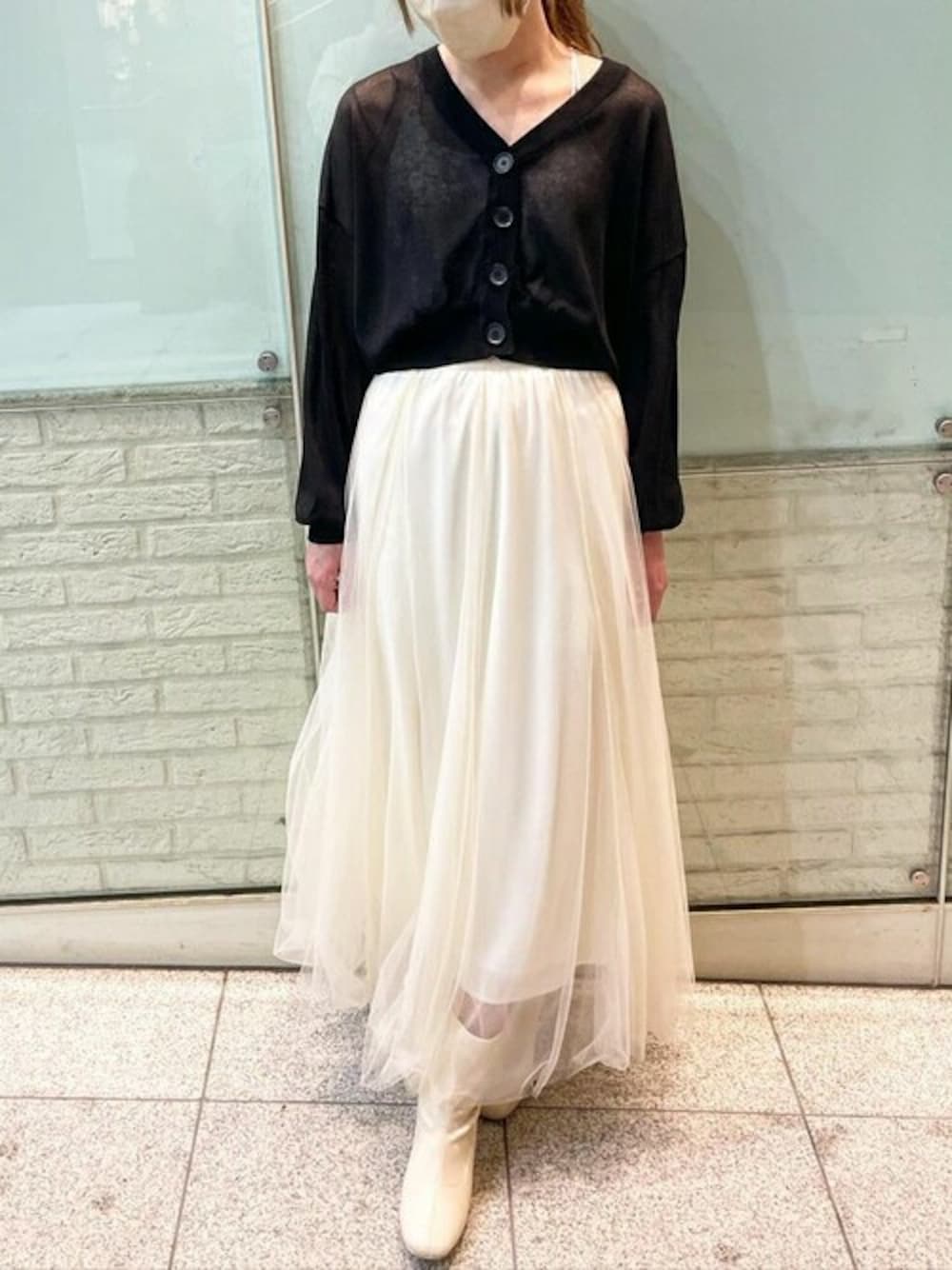 ブラック系のカーディガン/ボレロ、ホワイト系のスカートを着用したレディースの春コーディネートの1枚目の写真