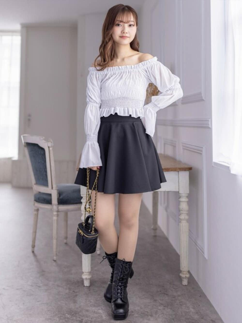 ホワイト系のシャツ/ブラウス、ブラック系のスカート、ブラック系のブーツを着用したレディースの春コーディネートの1枚目の写真