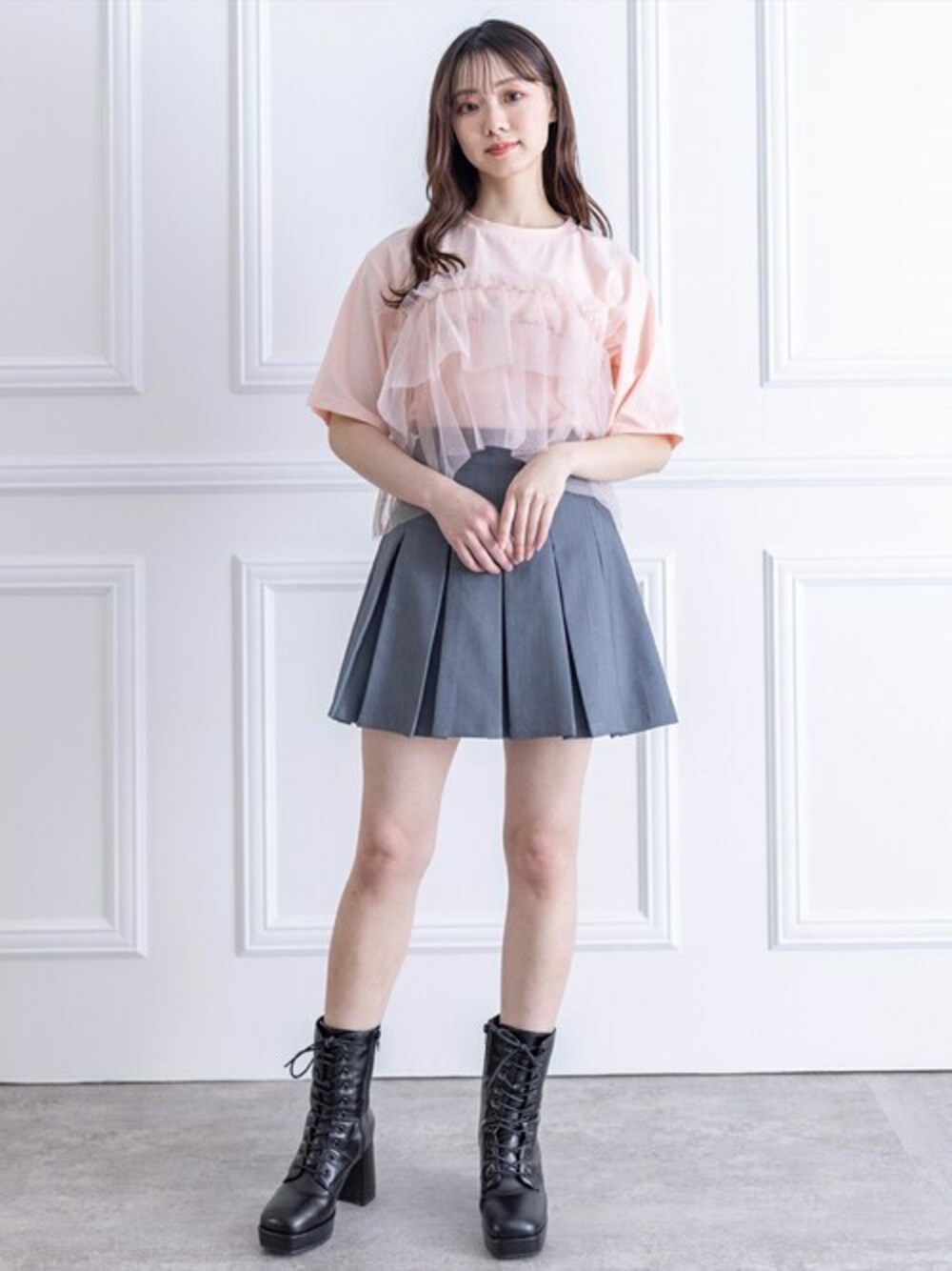ピンク系のTシャツ/カットソー、グレー系のスカート、ブラック系のブーツを着用したレディースの春コーディネートの1枚目の写真