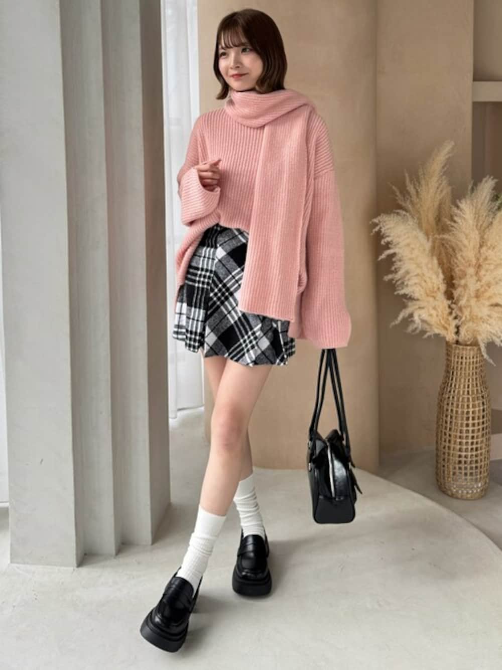 ピンク系のニット/セーター、ブラック系のスカート、ブラック系のローファーを着用したレディースの冬コーディネートの1枚目の写真
