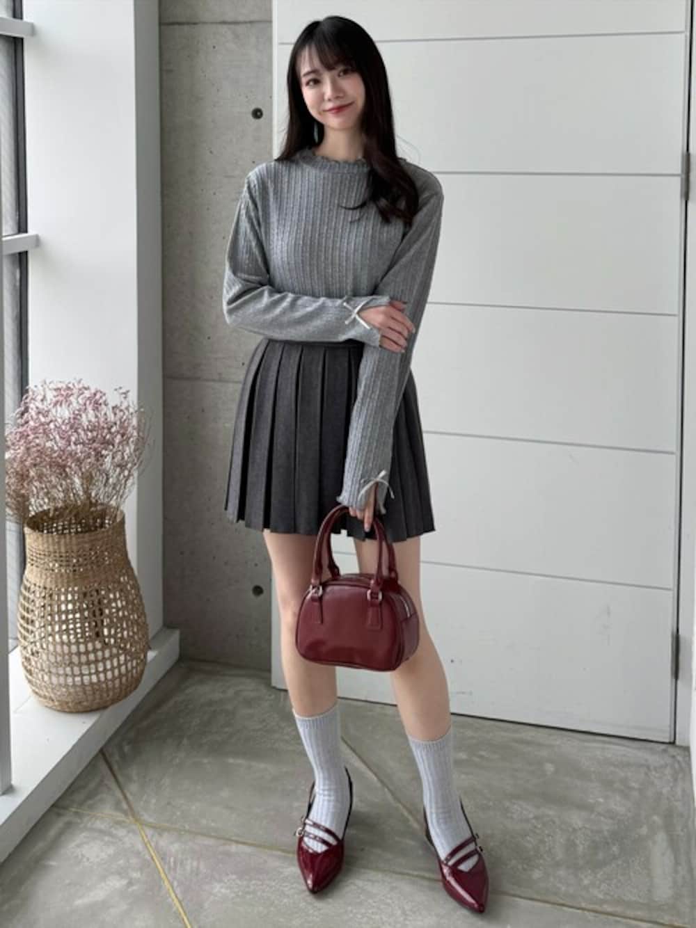 グレー系のスカート、レッド系のハンドバッグ、グレー系のTシャツ/カットソーを着用したレディースの冬コーディネートの1枚目の写真