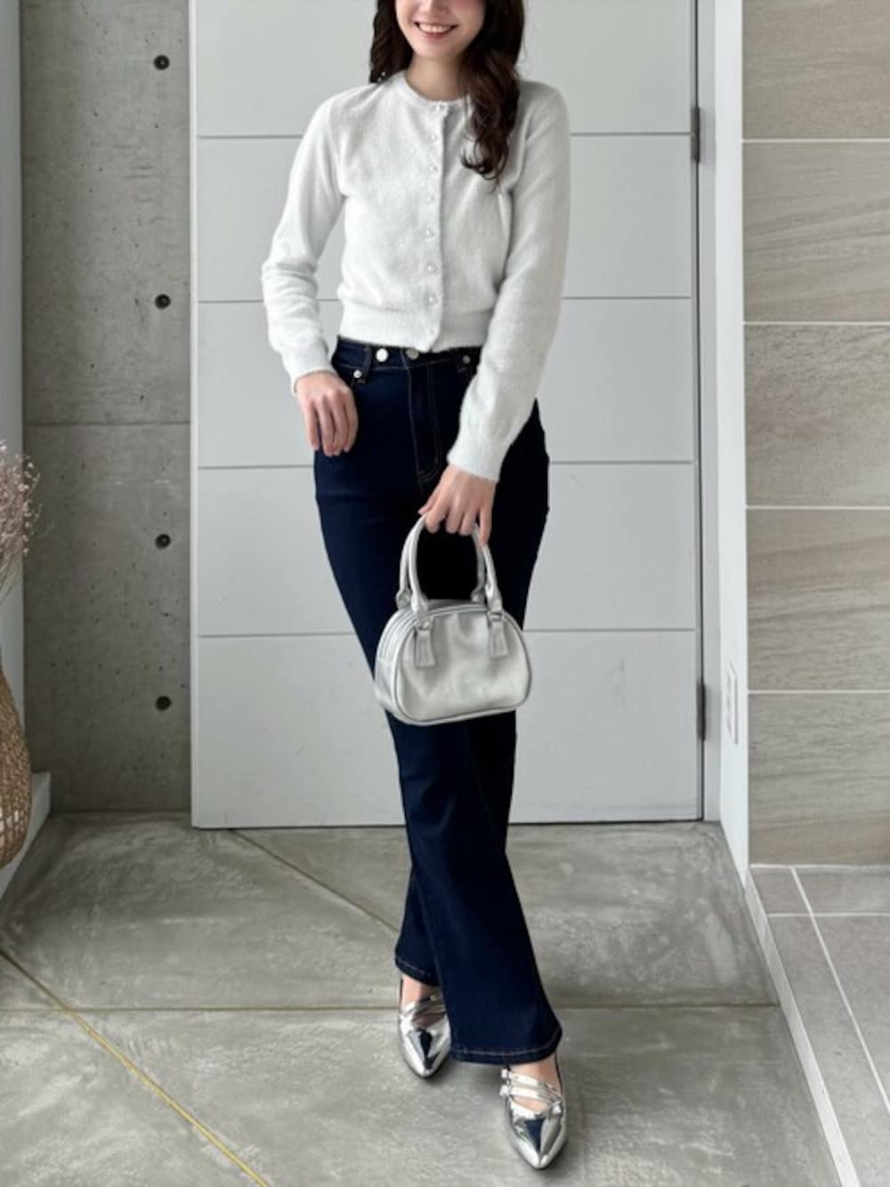 ホワイト系のカーディガン/ボレロ、ブルー系のデニムパンツ、シルバー系のハンドバッグを着用したレディースの冬コーディネートの1枚目の写真