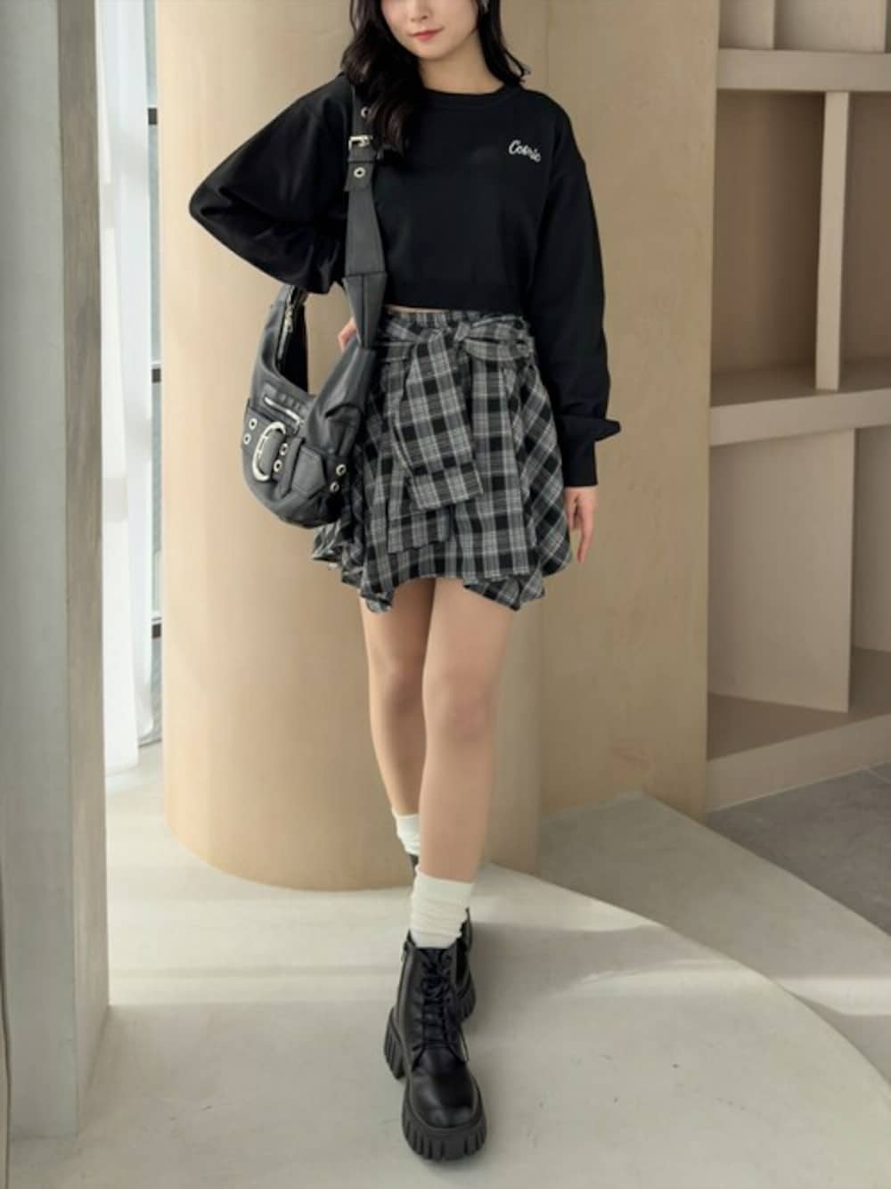 ブラック系のスカート、ブラック系のニット/セーター、ブラック系のブーツを着用したレディースの春コーディネートの1枚目の写真