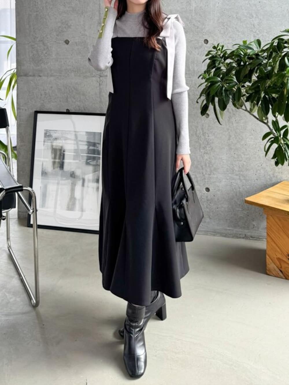 グレー系のニット/セーター、ブラック系のワンピース、ブラック系のブーツを着用したレディースの春コーディネートの1枚目の写真