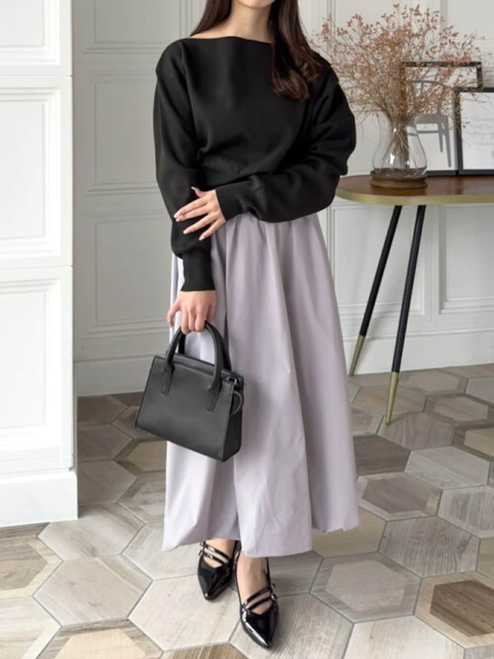 ブラック系のニット/セーター、ブラック系のパンプス、ブラック系のショルダーバッグを着用したレディースの春コーディネートの1枚目の写真