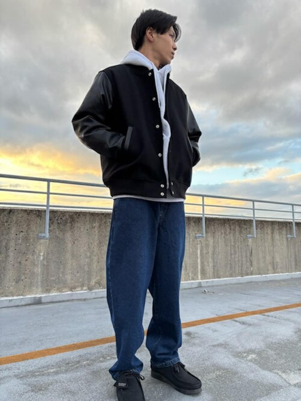 グレー系のパーカー、ブラック系のスタジャンを着用したメンズの冬コーディネートの1枚目の写真