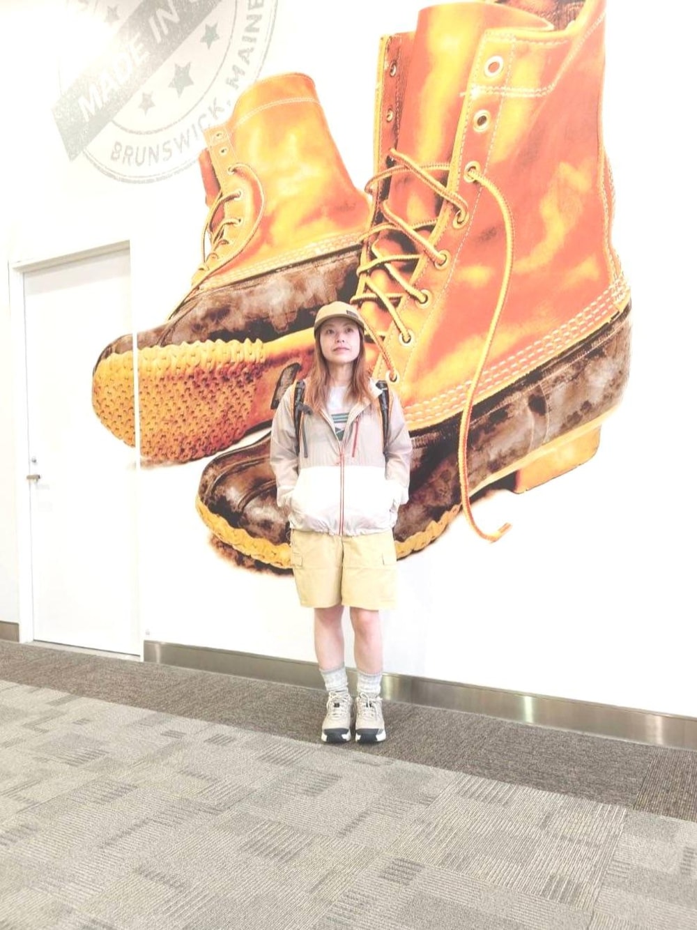 ベージュ系のその他パンツ、オレンジ系のバックパック/リュック、ベージュ系のキャップを着用したレディースの春コーディネートの1枚目の写真