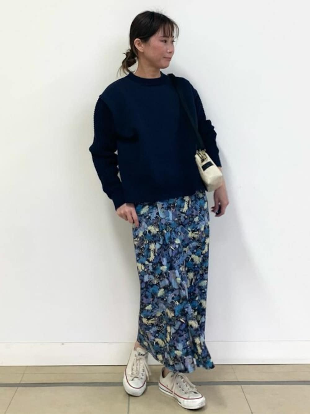 ブルー系のニット/セーター、ブルー系のスカート、ホワイト系のショルダーバッグを着用したレディースの冬コーディネートの1枚目の写真