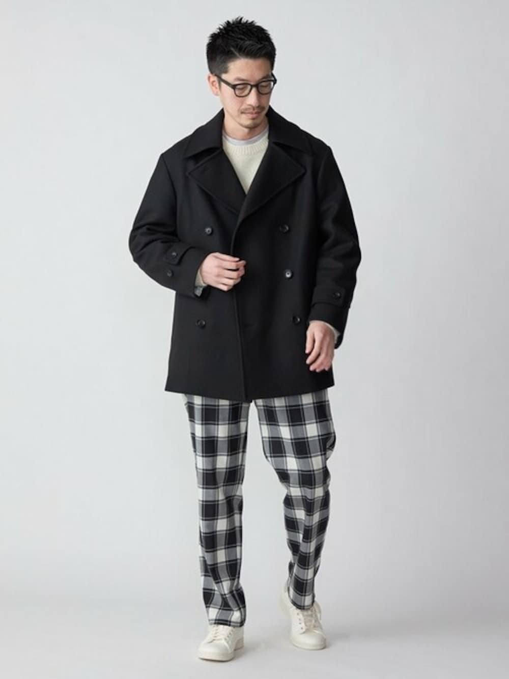 ホワイト系のニット/セーター、ブラック系のスラックス、グレー系のスニーカーを着用したメンズの冬コーディネートの1枚目の写真