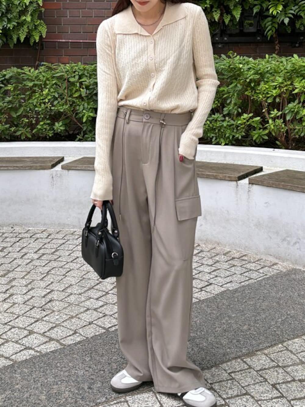 ホワイト系のポロシャツ、ベージュ系のスラックスを着用したレディースの冬コーディネートの1枚目の写真