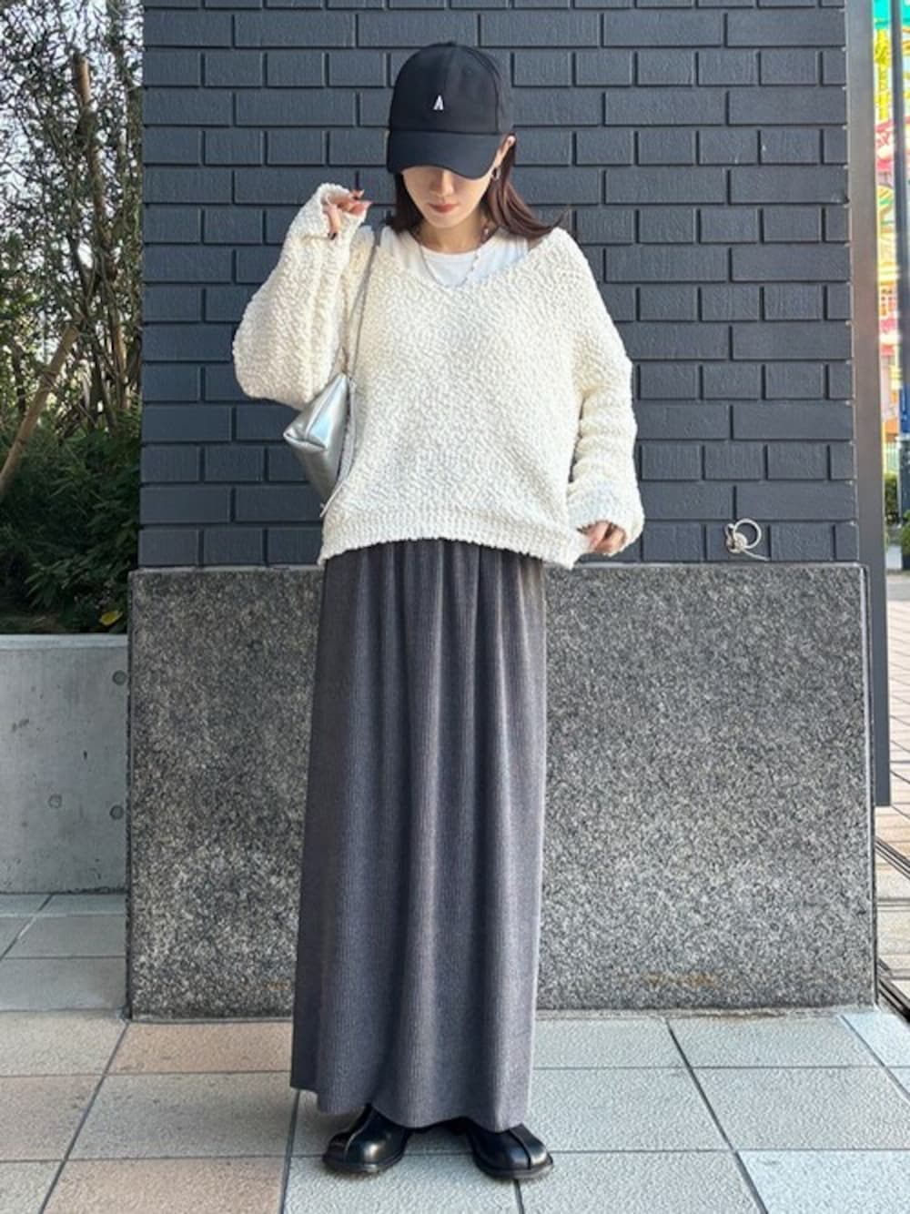 グレー系のスカート、ホワイト系のニット/セーターを着用したレディースの冬コーディネートの1枚目の写真