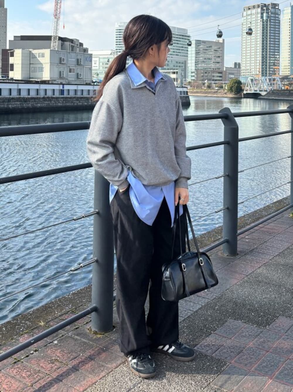 グレー系のポロシャツ、ブラック系のチノパンツ、ブルー系のシャツ/ブラウスを着用したレディースの冬コーディネートの1枚目の写真