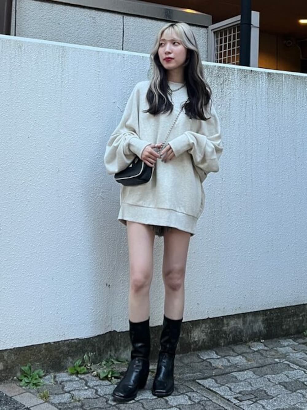 グレー系のスウェット、ブラック系のブーツ、ブラック系のデニムパンツを着用したレディースの秋コーディネートの1枚目の写真