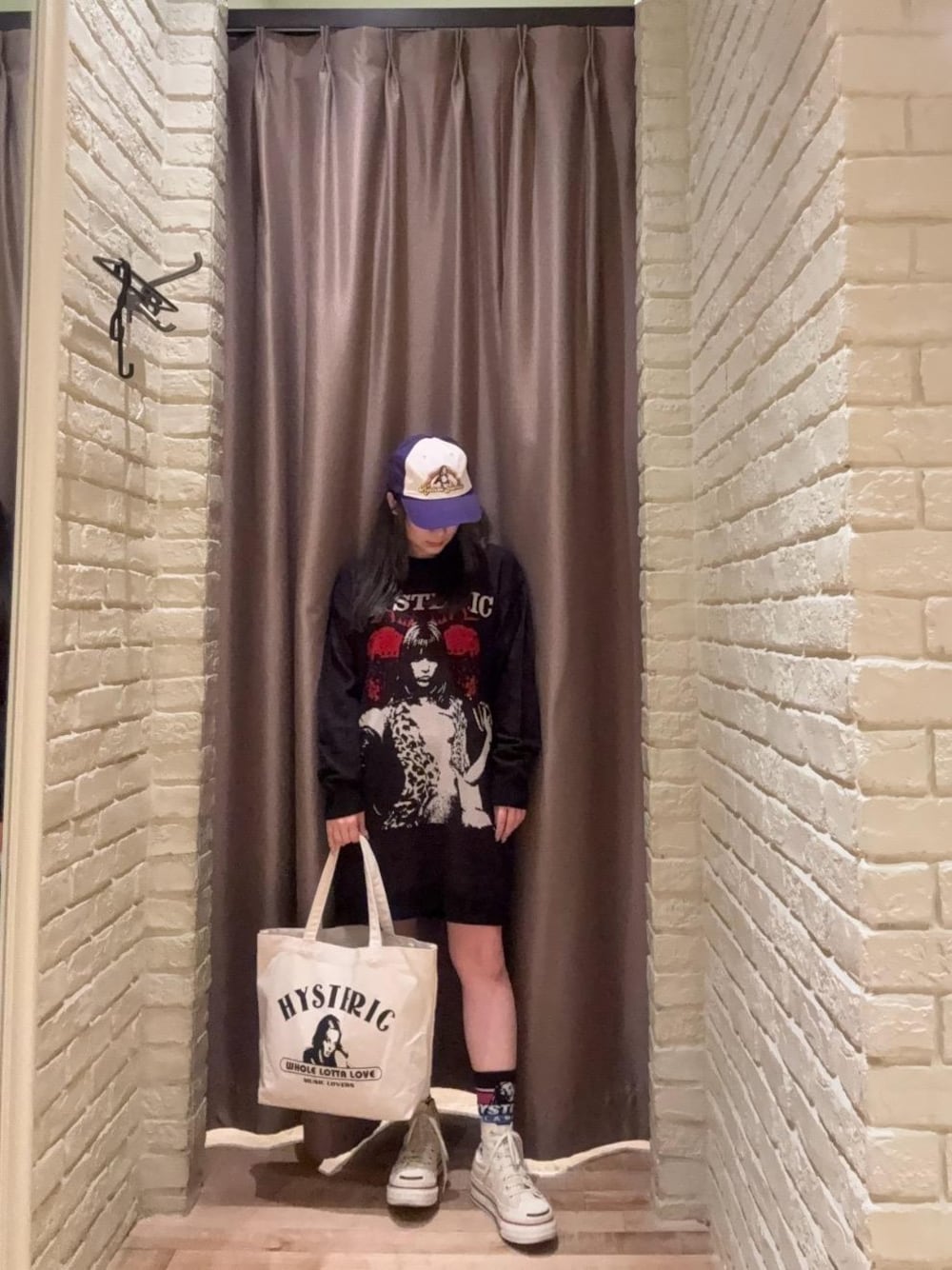 ブラック系のワンピース、ブラック系のトートバッグ、パープル系のキャップを着用したレディースの秋コーディネートの1枚目の写真