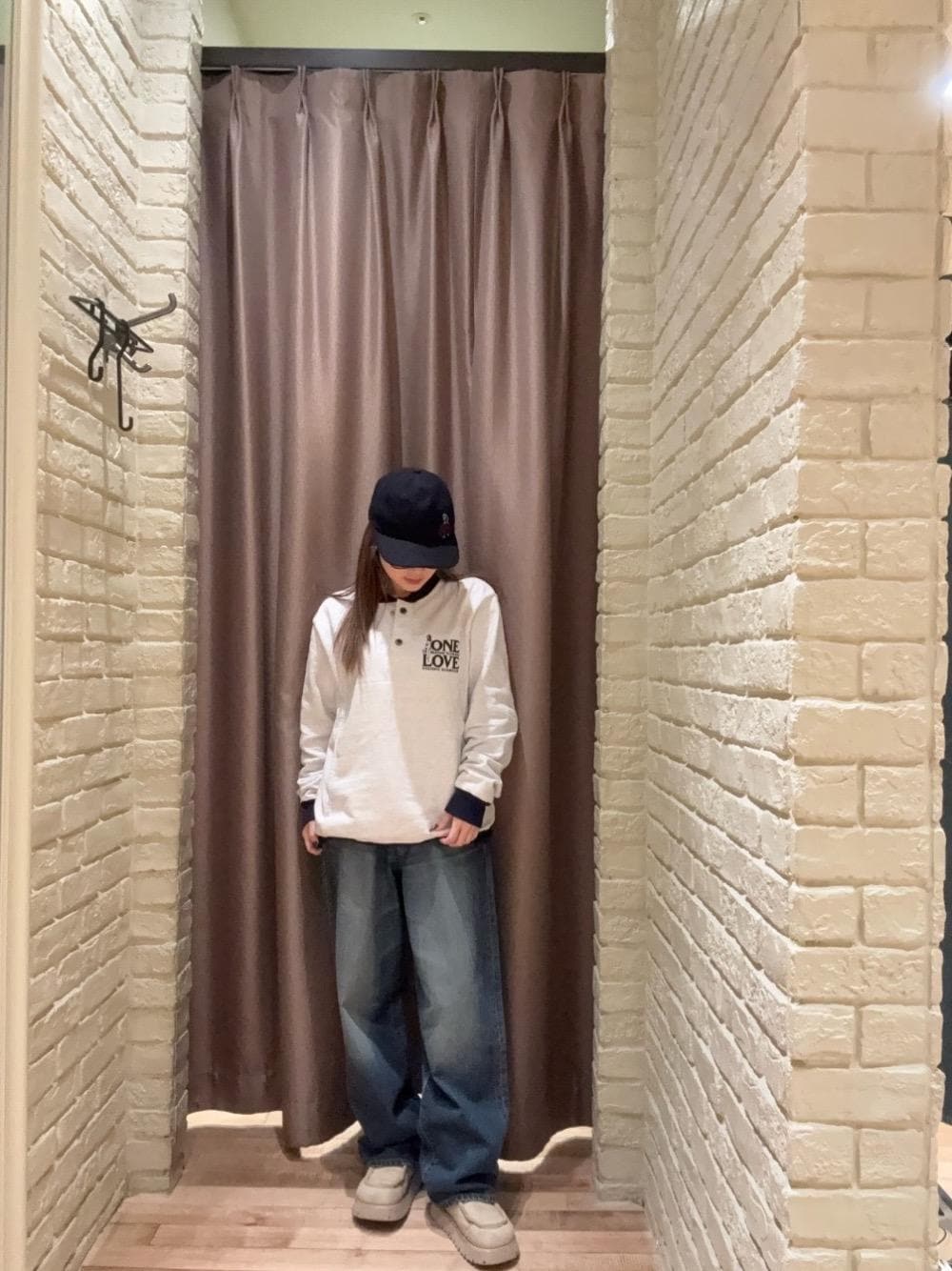 グレー系のスウェット、ブルー系のデニムパンツ、ブルー系のキャップを着用したレディースの秋コーディネートの1枚目の写真