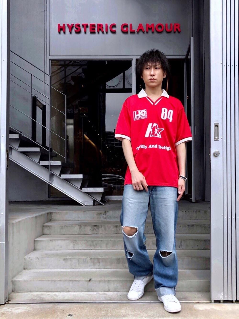 レッド系のTシャツ/カットソー、ブルー系のデニムパンツを着用したメンズの春コーディネートの1枚目の写真