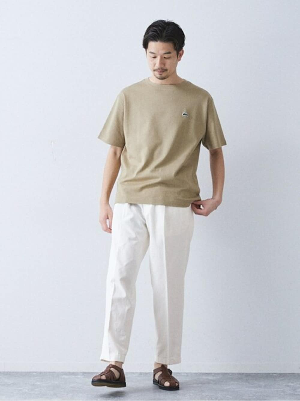 ホワイト系のデニムパンツ、ベージュ系のTシャツ/カットソー、ブラウン系のサンダルを着用したメンズの春コーディネートの1枚目の写真