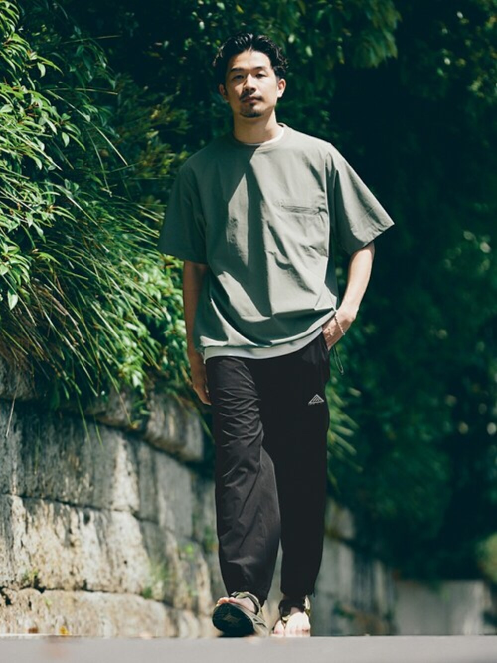 グリーン系のTシャツ/カットソー、ブラック系のカーゴパンツを着用したメンズの春コーディネートの1枚目の写真