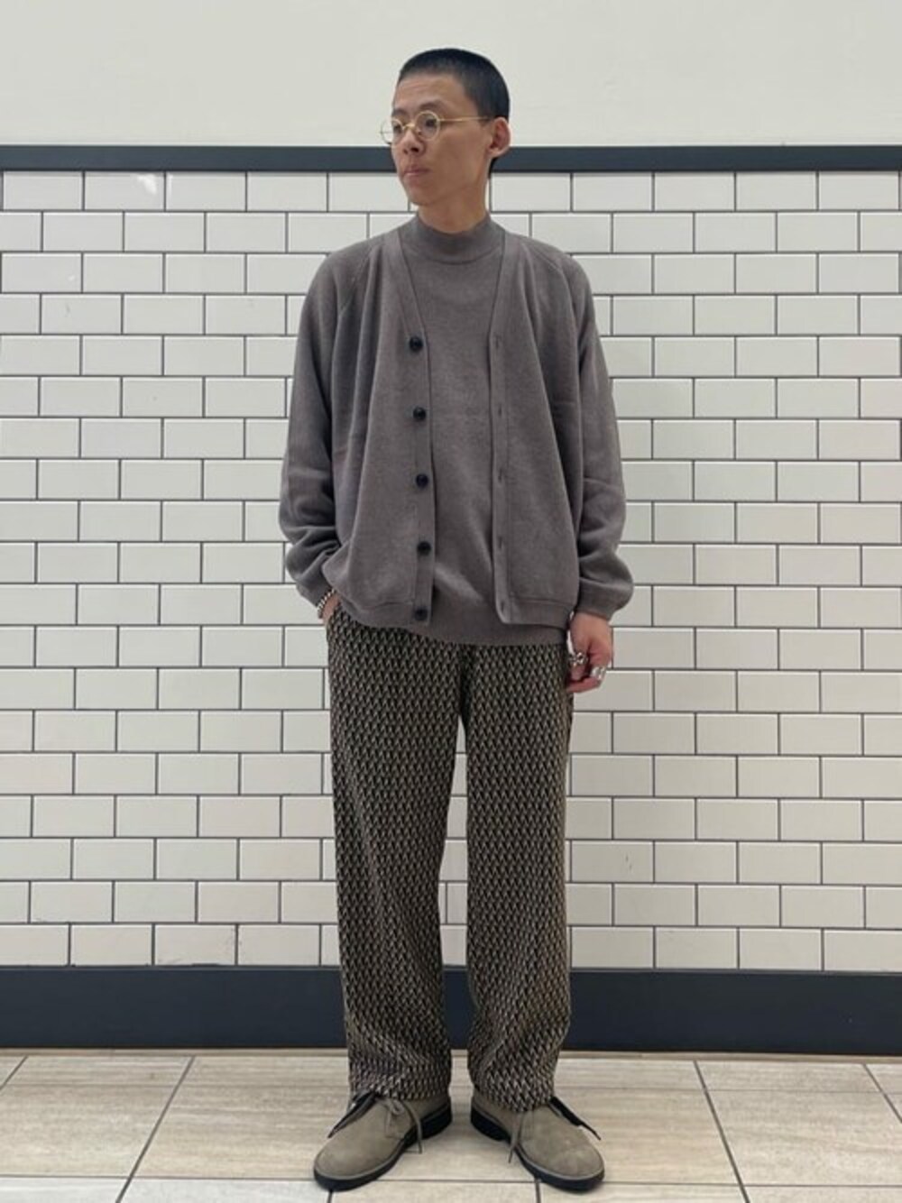 ブラウン系のカーディガン/ボレロ、ブラウン系のニット/セーター、ベージュ系のスラックスを着用したメンズの秋コーディネートの1枚目の写真