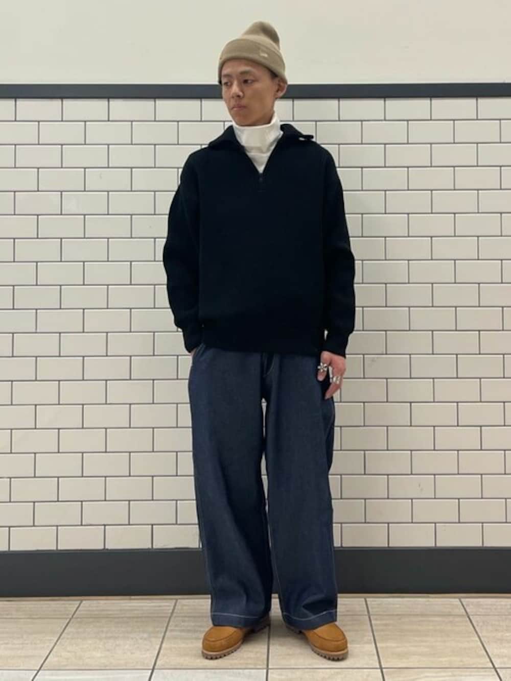 ブラック系のニット/セーター、ホワイト系のTシャツ/カットソー、ブルー系のデニムパンツを着用したメンズの秋コーディネートの1枚目の写真