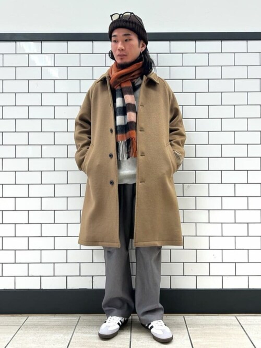 ベージュ系のステンカラーコート、グレー系のニット/セーター、グレー系のカーゴパンツを着用したメンズの冬コーディネートの1枚目の写真